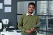 © AnnaStills - Portrait of African American businessman looking at camera standing in modern office with his workplace in background