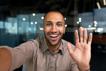 Smiling And Cheerful Businessman In Office Taking Selfie Photo On Phone And Talking On Video Call With Colleagues And Friends Using Smartphone, African American Man Waving At Camera Greeting Gesture.
