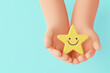 © Sookko3D - Hand holding yellow star happy smile face, good feedback rating, positive review, satisfaction survey, mental health assessment, child wellness, world mental health day, Compliment Day. 3d rendering
