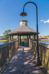 Wall Mural - Wooden pathway with railings and hook post light at Navarre, Florida. Pathway heading to a gazebo with views of the lake at the front of the houses at the back.