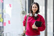 © David - Young curly Indian student Asian woman wearing backpack headphones holding books and tablet in office blue background.