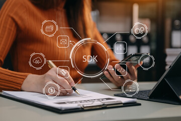 SDK  Software development kit programming language technology concept, Person typing laptop computer and tablet with SDK icon on virtual screen. in office.