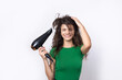 © Budjak Studio - A cute young girl dressed in a green top dries her beautiful long silky hair with a hair dryer against a white background.