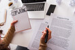 © LIGHTFIELD STUDIOS - Cropped view of copywriter holding marker and notebook near devices at home.