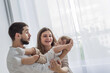 © Nastassia - Mom and dad laughing embracing little son tickling enjoying family lifestyle games at home