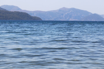 Wall Mural - View to blue sea and mountain island on horizon in mist. Water surface, background for traveling and vacation