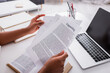 © LIGHTFIELD STUDIOS - Cropped view of freelancer holding papers with copywriting lettering near book and laptop at home.
