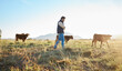 © K Davis/peopleimages.com - Man, farmer and animals in the countryside for agriculture, travel or natural environment in nature. Male traveler on farm walking on grass field with livestock leading the herd of cattle or cows