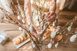 © Elena Medoks - Close-up of a girl's hands hanging a decorative Easter egg on a willow branch at home. Decorating your home for Easter