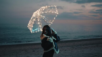 Wall Mural - Pretty model girl with glowing umbrella on the beach near the ocean
