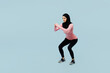 Full body side view calm young asian muslim fitness trainer sporty woman wear pink abaya hijab spend time in home gym do squates isolated on plain blue background studio Workout sport fit abs concept
