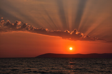 Wall Mural - Beautiful Aegean sunset over Seferihisar hills in Izmir with an orange evening sky and light reflected in a dark calm sea