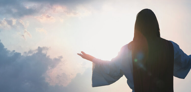 Easter Christian concept with cross Jesus Christ praying earnestly giving glory to God towards bright light sky
