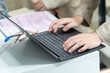 © Surachetsh - Employee’s hand  using office computer Typing an email on a computer keyboard and doing online research working in an office.