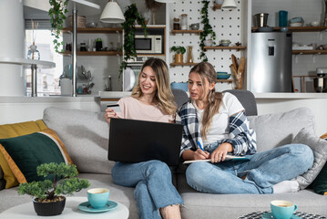 two young women and best friends doing online shopping at home with a laptop and a credit card from 