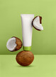 White cosmetic tube on green background. Minimal styling scene with coconut, still life. Beauty blogging, skincare