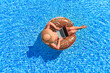 Smart modern woman traveler floating on inflatable rubber circle and browsing online using computer by the swimming pool. Leisure weekend and remote freelance work concept