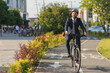 © Tymoshchuk - Successful executive in suit smiling, while riding on bike path outside.