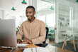 © mavoimages - Smiling young African businessman working on a computer in an office