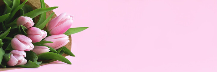 Wall Mural - Beautiful delicate bouquet of tulip flowers in craft wrapping paper on pink background banner. Panoramic web header with copy space. Wide screen wallpaper