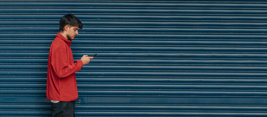 Poster - young man walking on the street looking at mobile phone or smartphone