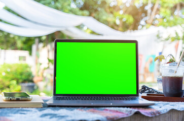 Wall Mural - Mockup of laptop computer with empty screen with coffee cup and smartphone on table beside the window of the coffee shop background,White screen