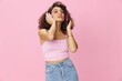 © SHOTPRIME STUDIO - Happy woman wearing headphones with curly hair listening to music and singing along with her eyes closed in a pink T-shirt and jeans on a pink background DJ party, copy space