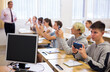 © JackF - Group of modern teenagers sitting with mobile phones on lesson in classroom