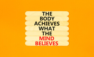 Mind and body symbol. Concept words The body achieves what the mind believes on wooden stick. Beautiful orange table orange background. Copy space. Motivational mind and body concept.