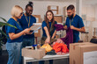 © Zamrznuti tonovi - Diverse volunteers working in a charity donation center and packing clothes and food