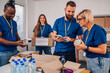 © Zamrznuti tonovi - Diverse volunteers working in a charity donation center and packing clothes and food