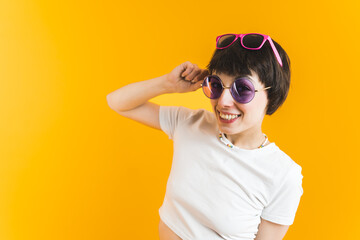 Funny young caucasian girl with two pairs of sunglasses. Gen Z humor. Isolated over orange background. Medium closeup studio shot. High quality photo