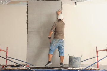 Poster - Worker installing tile on wall indoors, back view