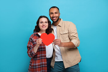 Poster - Lovely couple with red paper heart on light blue background. Valentine's day celebration