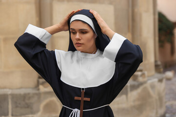 Wall Mural - Young nun with Christian cross near building outdoors