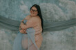 fat woman with glasses and dark hair with hidradenitis suppurativa holding blue fabric 
