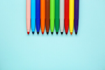 Poster - Different colorful markers on light blue background, flat lay. Space for text