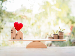 Plants growing up on stack of coins and miniature house on balancing scale for mortgage investment , property concept