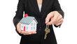 © Maridav - Real estate agent new house keys concept. Realtor showing holding house keys and mini house model. Buying new home conceptual image with business woman in suit isolated in transparent PNG
