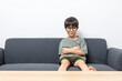 © bennnn - Cute Asian boy with eyeglasses looking up or right, sitting on a sofa at home. Curious kid thinking.