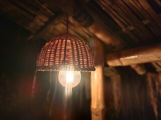 Bamboo pendant light lamp hanging on a resort balcony.  Closeup of hanging light bulbs and decorative bamboo craft Edison on a resort balcony. Blurred background. 