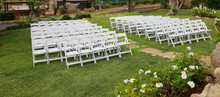 White Resin Folding Chairs With Padding Arranged For Wedding Ceremony.