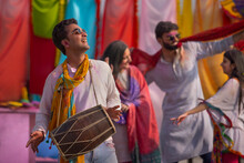A Group Of Young Men And Women Happily Dancing Together While Celebrating Holi