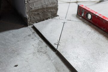 Wall Mural - Laying ceramic tiles on the floor according to the level - a professional tiler performs the interior decoration of the room