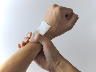 close up of a person with a sprained wrist, with an anti-inflammatory, pain relief patch on the left