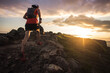 © Cavan Images - Trail running man running at sunrise with cairn from low angle
