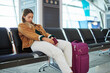 © Nina L/peopleimages.com - Bored woman, airport and luggage waiting with passport for flight, travel or vacation journey in Cape Town. Tired female traveler sitting in wait for delay departure, plane cancel or immigration