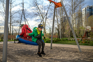 Wall Mural - Two little kid boys having fun with swing on outdoor playground. Children, best friends and siblings swinging on warm sunny spring or autumn day. Active leisure with kids. Casual boy fashion