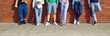 Group of friends. Legs of people standing in row on background of brick wall dressed in stylish youth casual clothes. Young men and women posing in various denim shorts and pants. Low section.