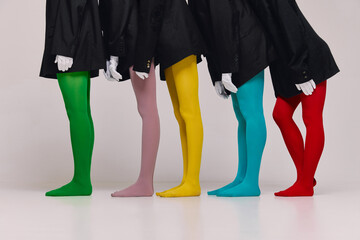 Wall Mural - Cropped image of women in black jackets and multi colored tights standing together over grey background. Concept of beauty, feminism, emotions, extraordinary fashion